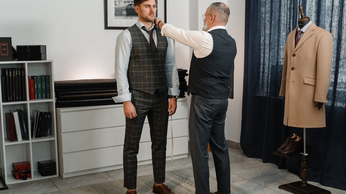 Tailor measuring a client's suit for a perfect fit in a stylish fashion studio.